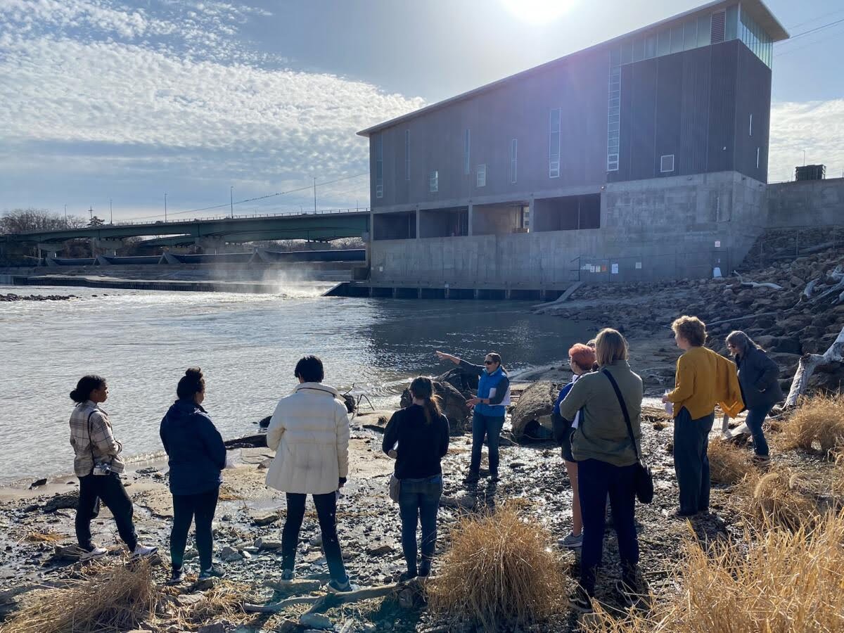 Professor points to river as students listen