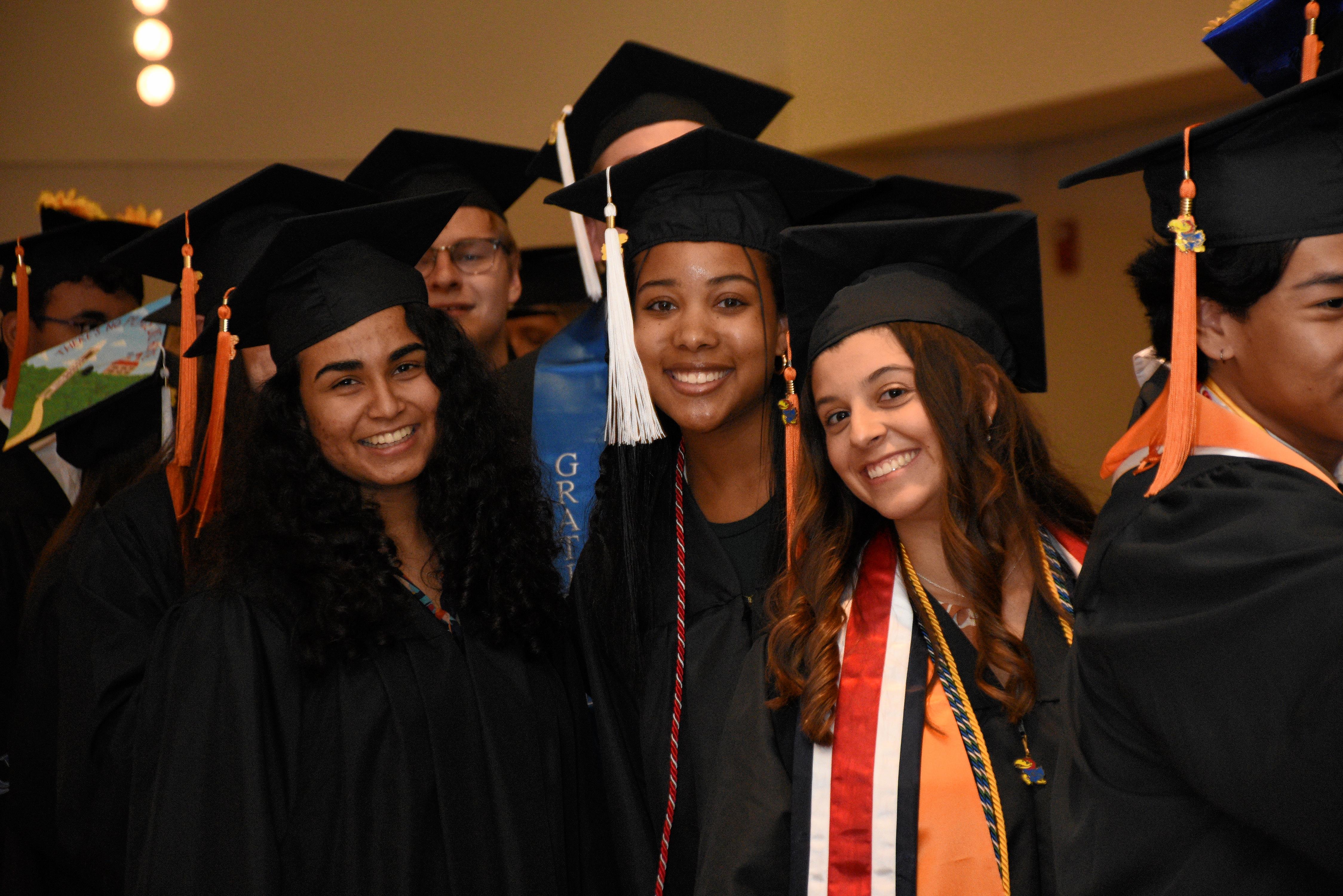 Three women in graduation caps and gowns smile